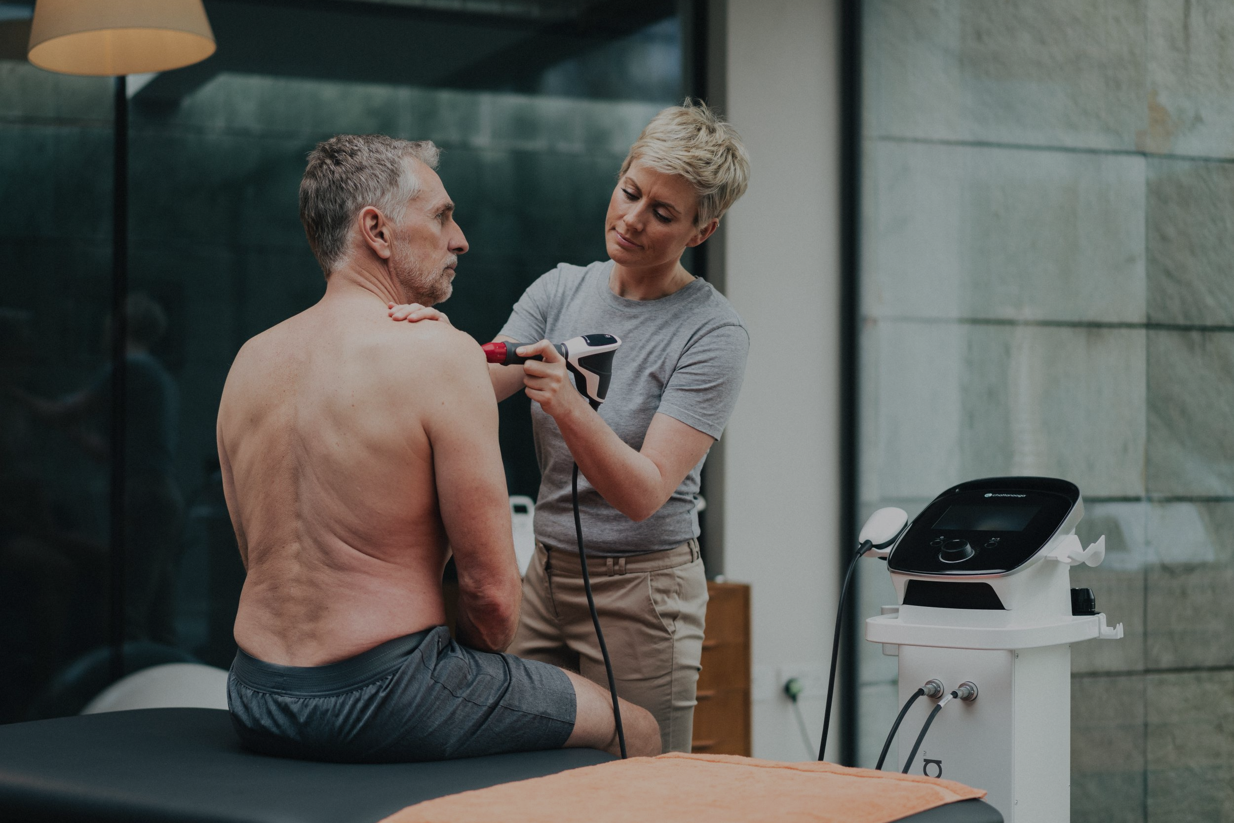 doctor using shockwave on patient shoulder