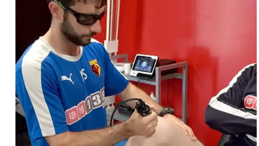 clinician applying laser to knee in athletic training room