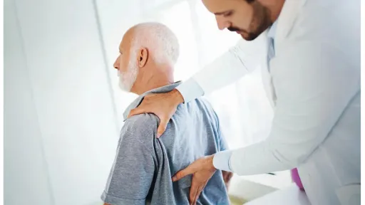 doctor assessing elder patient lower back