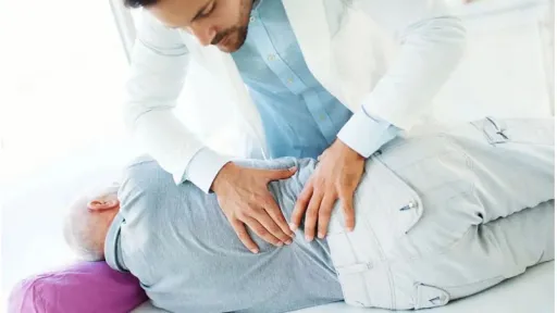 doctor assessing elder patient's lower back