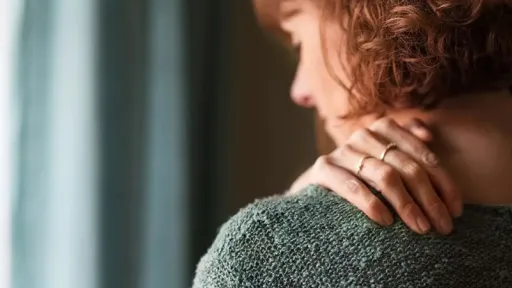 woman rubbing shoulder in pain