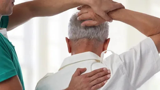 doctor pulling elder patient arm over his head, testing range of motion