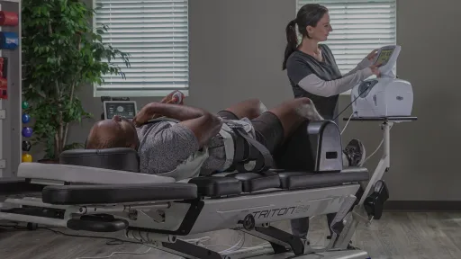 patient on traction table, clinician adjusting traction device